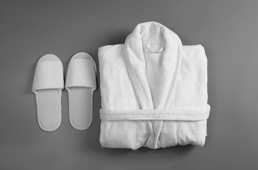 Clean folded bathrobe and slippers on grey background, flat lay - obrazy, fototapety, plakaty