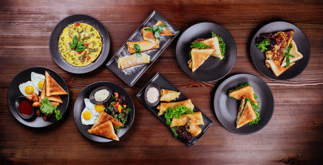 Breakfast foods includes pancakes, eggs and bacon, biscuits, scrambled eggs, cinnamon muffins, fresh blueberries, pancake balls, and cinnamon rolls with icing.