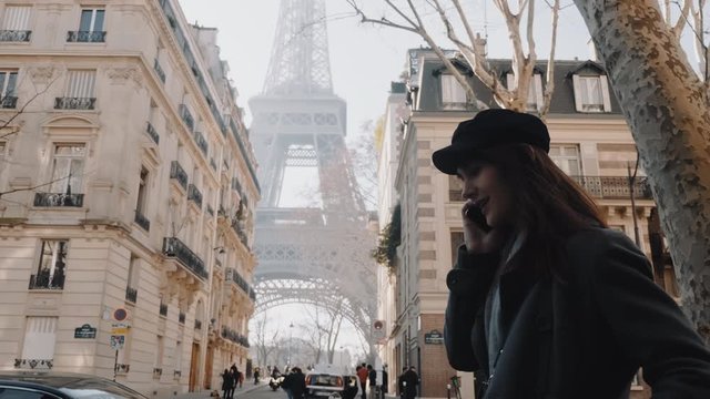 Side view beautiful smiling young woman talking on phone, sunny autumn Paris Eiffel Tower seen in background slow motion