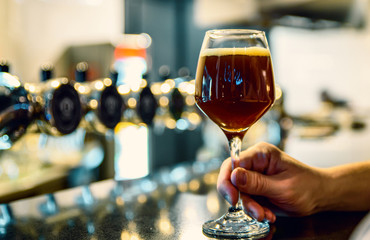man holds a glass of beer in his hand at the bar or pub