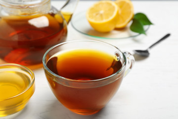 Delicious tea with honey and lemon on white table