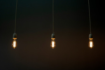 Three light bulbs light bulbs dimly glow in the dark Dim lighting of the space Dark background, barely lit by three lamps