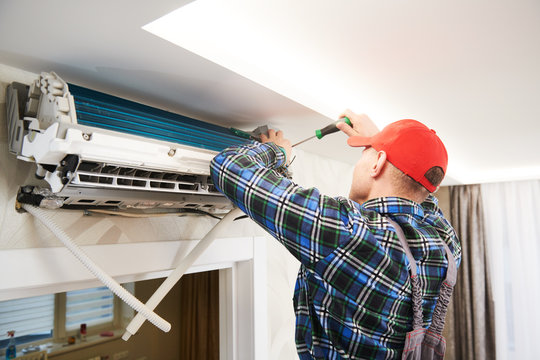 Air conditioner service. Worker at climatization system installation indoors