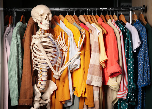 Artificial human skeleton model among clothes in wardrobe