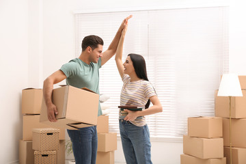 Happy couple in room with cardboard boxes on moving day