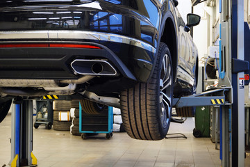 Modern luxury car SUV on a lift in a service center. The concept of service and repair of a modern luxury car.