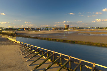 Obraz premium View of River Arun entering the sea at low tide with Littlehampton in the background on a beautiful warm summers day.