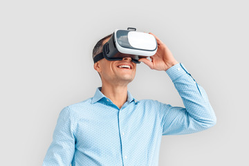 Freestyle. Mature businessman in virtual reality headset standing isolated on white watching video happy