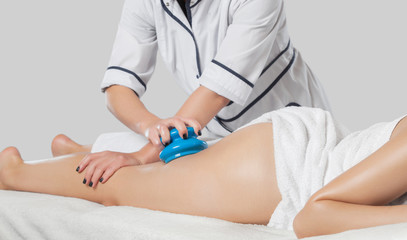 A masseur makes anti-cellulite massage on the legs, thighs, hips and buttocks with a vacuum massager in the spa. Overweight treatment, body sculpting.Cosmetology and massage concept.
