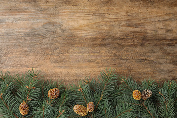 Top view of fir branches on wooden background, space for text. Winter holidays