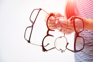 woman's hands holding few pairs of glasses isolated on white. Spectacles presentation. Closeup
