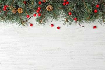 Flat lay composition with fir branches and berries on white wooden background, space for text. Winter holidays
