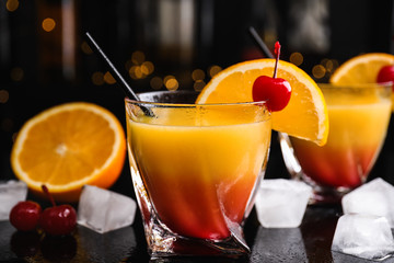 Fresh alcoholic Tequila Sunrise cocktail on black table
