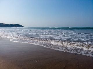 Foamy sea waves on shore. Foamy waves of clean sea water rolling on wet sandy beach on sunny day on resort
