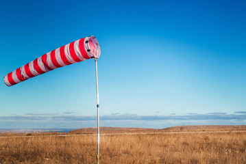 Striped weather vane against blue sky