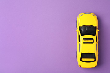 Yellow taxi car model on purple background, top view. Space for text