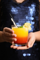 Woman with glass of Tequila Sunrise, closeup. Delicious alcoholic cocktail