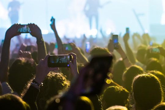  people having fun and dancing with their hands to the sky during a live music concert