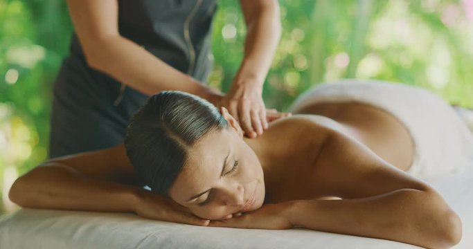 Attractive multi ethnic woman receiving a massage at a resort spa, blissful spa day, spa health and wellness concept