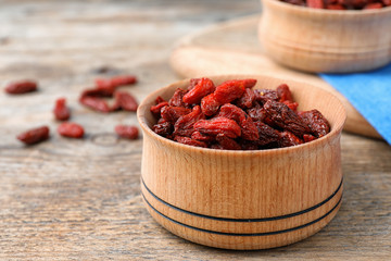 Dried goji berries in bowl on wooden table
