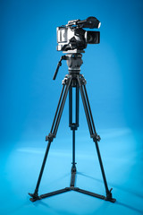 Modern professional video camera on blue background