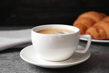 Tasty fresh croissants and coffee on grey table, closeup