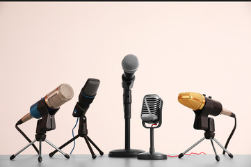 Different microphones on light grey table. Journalist's work