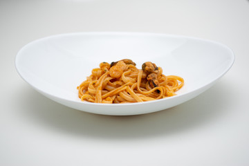 italian spaghetti with fish in white plate on white background