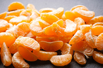 Slices of ripe tangerines on a dark background.