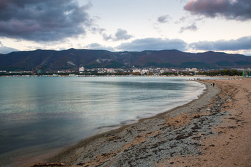 Evening winter beach in Gelendzhik. Blue evening. Long exposure. Clouds. Mountains in the background. Philosophical and thoughtful mood. 