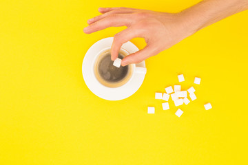 cropped view of woman adding lump sugar to coffee isolated on yellow