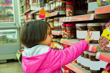 Little girl wants to buy chocolate from counter in the supermarket