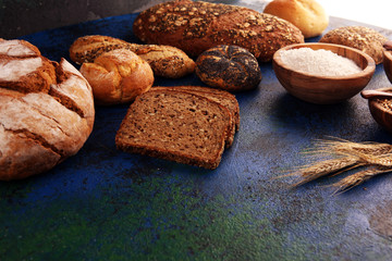 Assortment of baked bread and bread rolls and cutted bread on table background