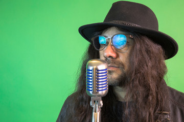Singer with beard, hat and long hair in front of retro microphone, hipster mood