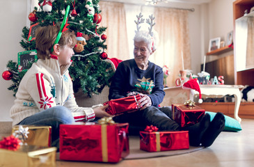 Obraz na płótnie Canvas grandmother and grandson by the Christmas tree with gifts from Santa Claus or wise men