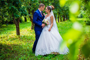 Bride and Groom at wedding Day walking Outdoors on spring nature. Bridal couple, Happy Newlywed woman and man embracing in green park. Loving wedding couple outdoor.