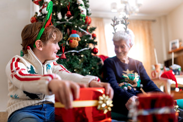 Obraz na płótnie Canvas grandmother and grandson by the Christmas tree with gifts from Santa Claus or wise men