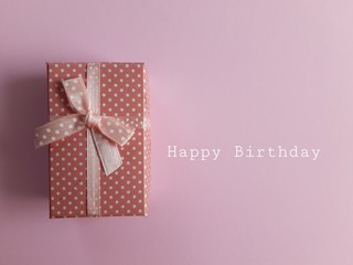 Birthday gift box with ribbon and bow on pink background