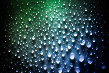 Drops of water with a beautiful smooth gradient in green and blue colors closeup macro on the material in the sunlight.