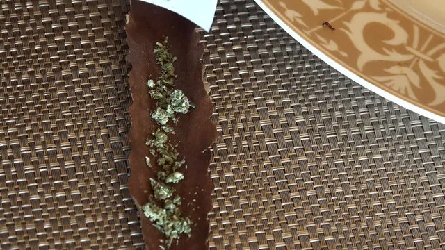 African American female hand putting cannabis into a Cigarillo