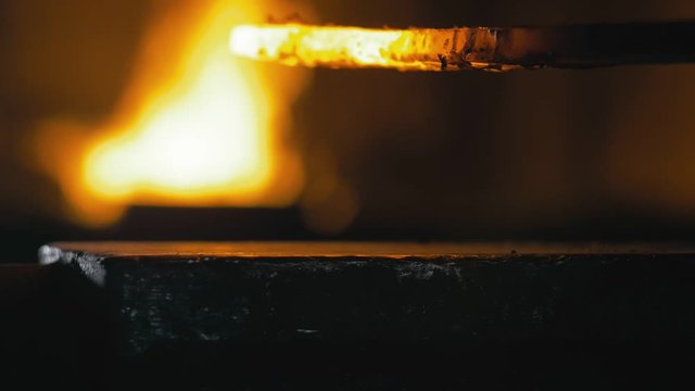 Forge workshop. Smithy manual production. Hands of smith with hammer hit on glowing hot metal, on the anvil, the forging process. Blacksmith makes iron products for manufacture of fireplace, stove.