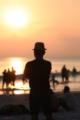 Fototapeta premium Back view of a man silhouette standing and watching sun