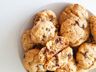 Homemade oatmeal cookies with pecan nuts and milk chocolate on a light grey plate on a white background