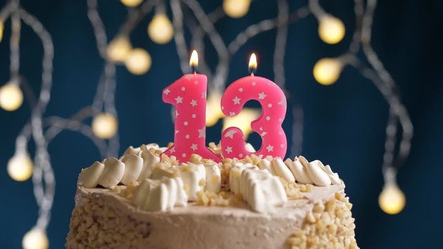 Birthday cake with 13 number pink candle on blue backgraund. Candles blow out. Slow motion and close-up view