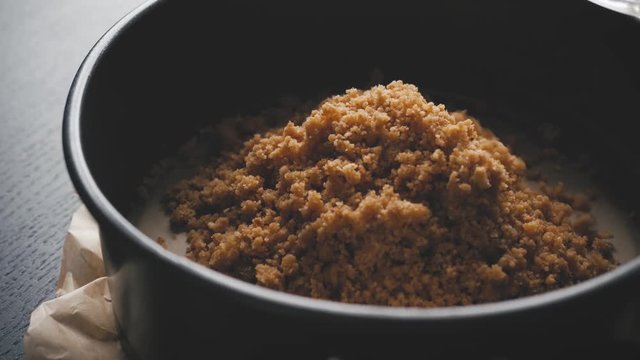 Putting crakers crumbs in a spring form pan. close up shot.