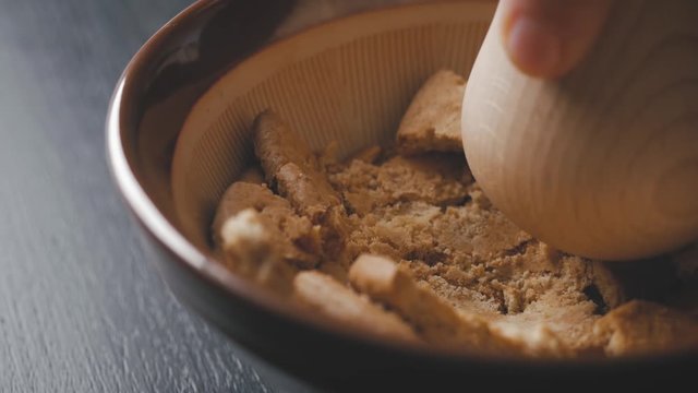 Crush crakers with a wood presser in a bowl. close up shot.