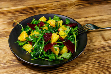 Tasty salad of fresh arugula, beetroot and oranges on wooden table. Healthy food or vegetarian concept