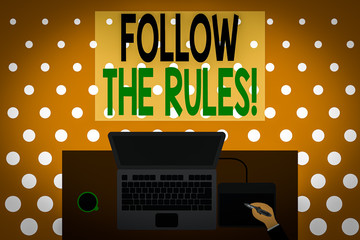 Word writing text Follow The Rules. Business photo showcasing go with regulations governing conduct or procedure Upper view laptop wooden desk worker drawing tablet coffee cup office