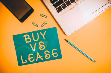 Conceptual hand writing showing Buy Vs Lease. Concept meaning Own something versus borrow it Advantages Disadvantages Trendy open laptop smartphone marker paper sheet clips