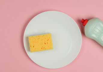 Washing dishes. Plate with sponges, a bottle of washing gel on pink pastel background. Top view. Studio shot.